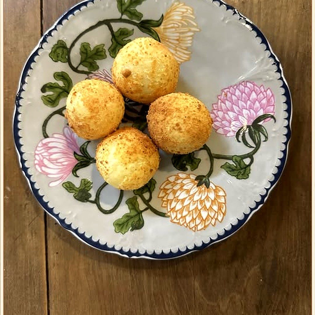 Pães de queijo em prato de louça pintada com flores
