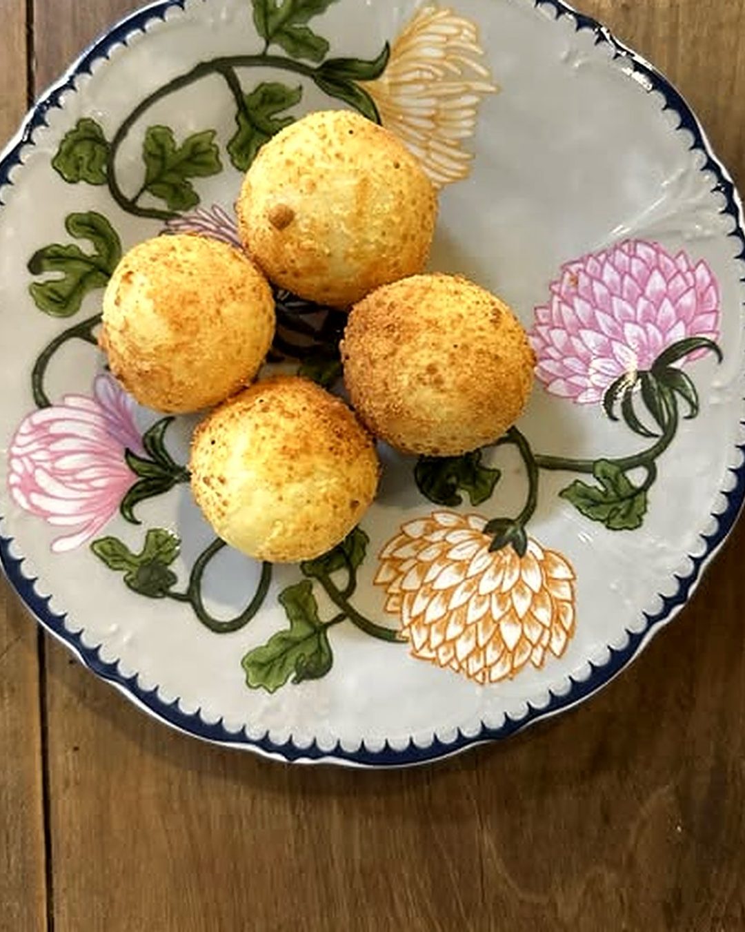 Pães de queijo em prato de louça pintada com flores