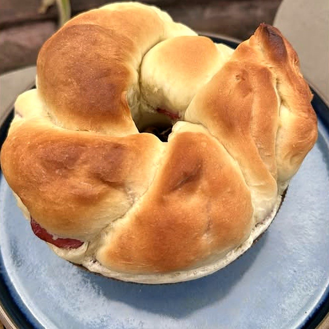 Rosca de calabresa trançada e dourada sobre prato azul